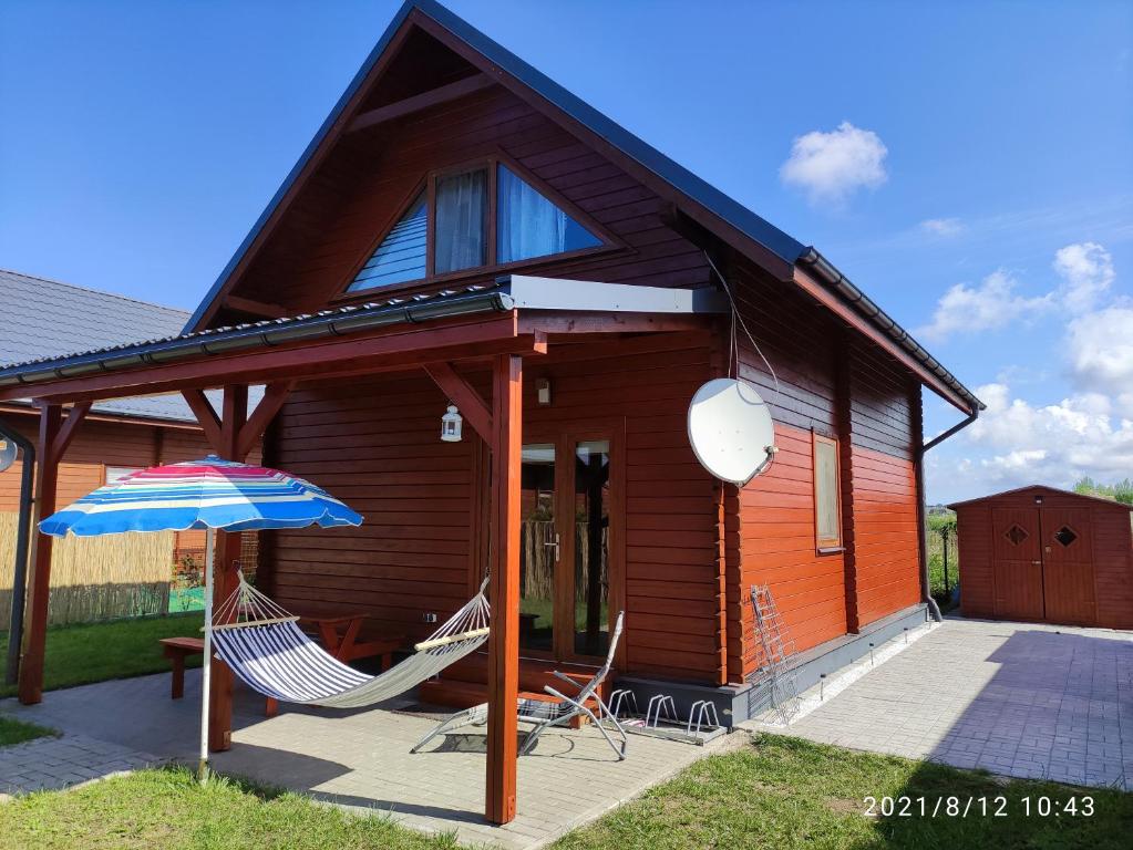 une maison avec deux chaises et un parasol dans l'établissement Przytulny domek, à Darłówko