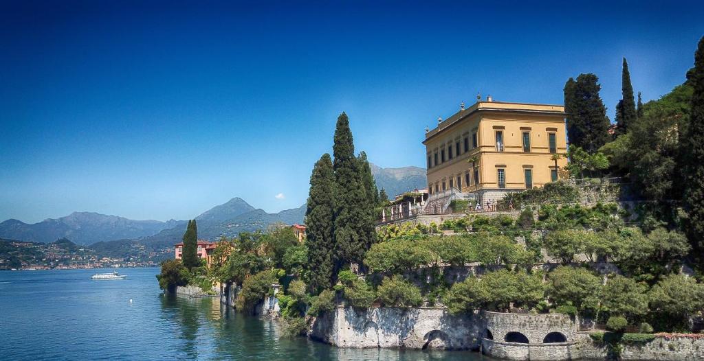 a building on a hill next to a body of water at Hotel Villa Cipressi, by R Collection Hotels in Varenna