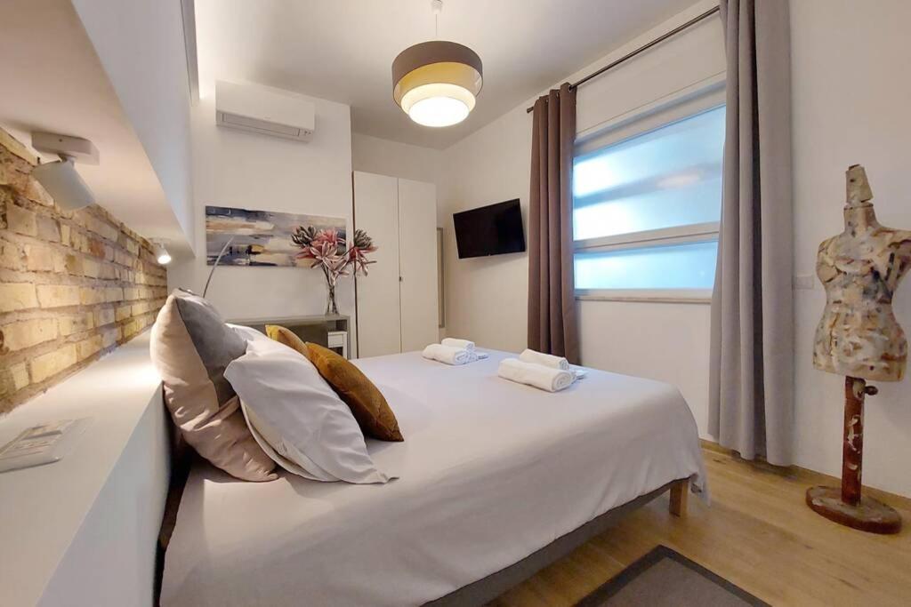 ein Schlafzimmer mit einem weißen Bett mit Kissen und einem Fenster in der Unterkunft Aventino Contemporary Apartment in Rom