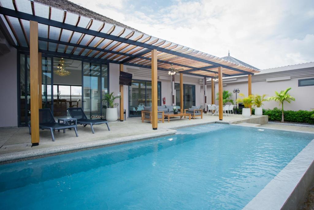 einen Pool mit einer Pergola neben einem Haus in der Unterkunft Gold Chariot Pool Villa, Phuket - SHA Plus Certified in Strand Bang Tao