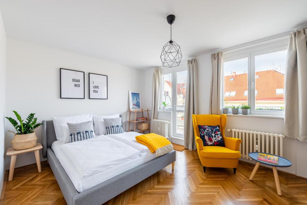 a bedroom with a bed and a yellow chair at BRIGHT CHARMING Apt with TERRACE, PARKING & AirCo. in Prague