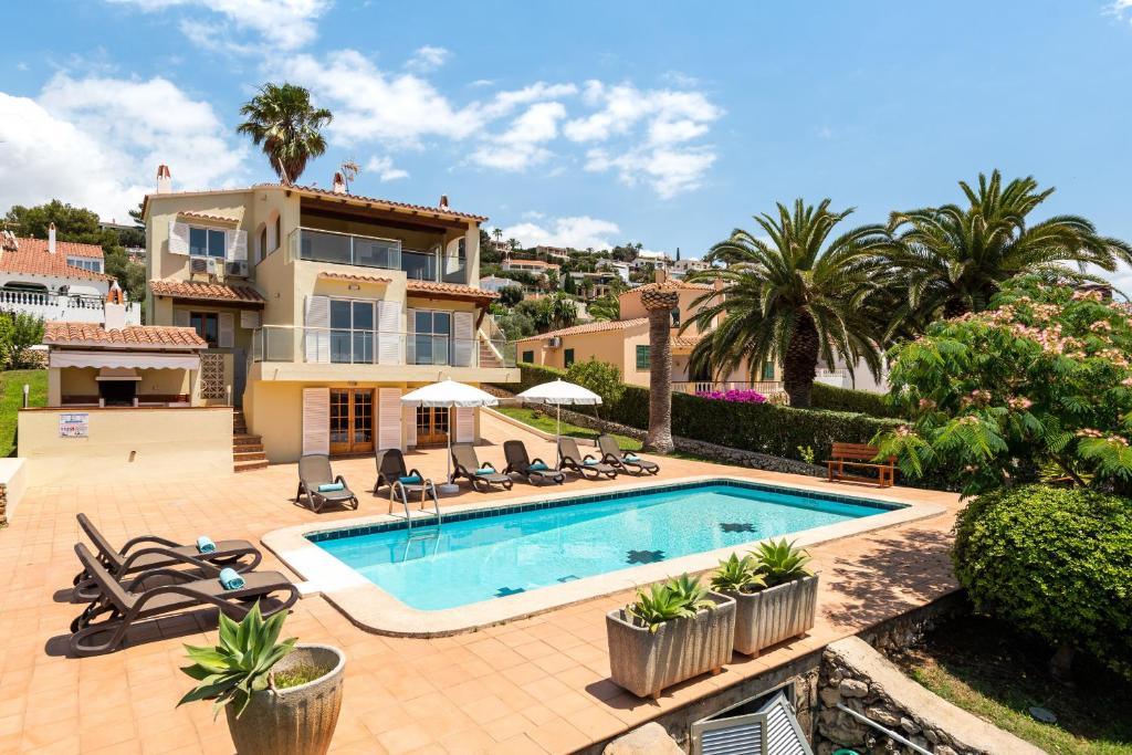 a villa with a swimming pool and palm trees at Villa Varadero by Escape Home in Alaior