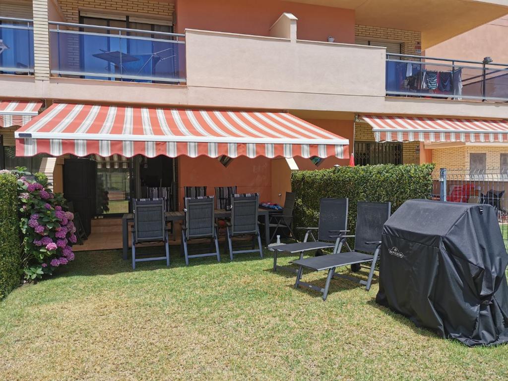 eine Terrasse mit Stühlen und ein Zelt auf dem Gras in der Unterkunft 6Beds Salou in Salou