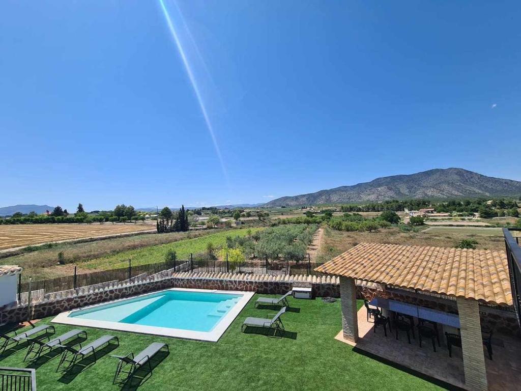 una piscina in un cortile con sedie e una casa di Casa Rural Las Tosquillas a Caravaca de la Cruz