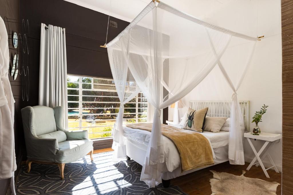 a bedroom with a canopy bed and a chair at Sweetfontein Boutique Farm Lodge in Britstown