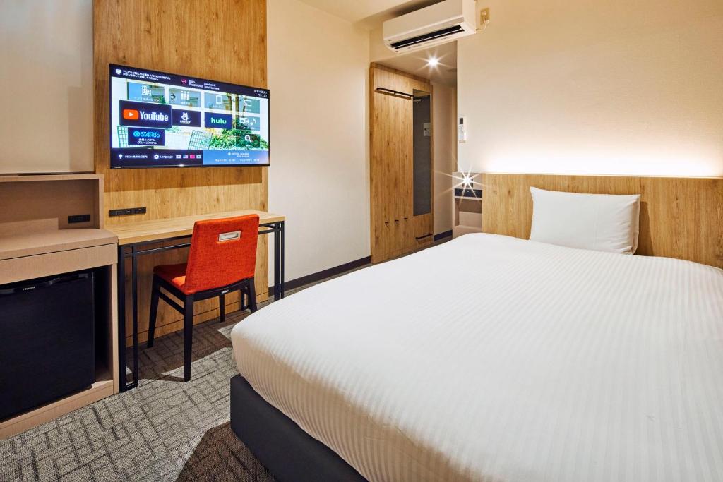 a hotel room with a bed and a tv at Hotel Lumiere Kasai in Tokyo