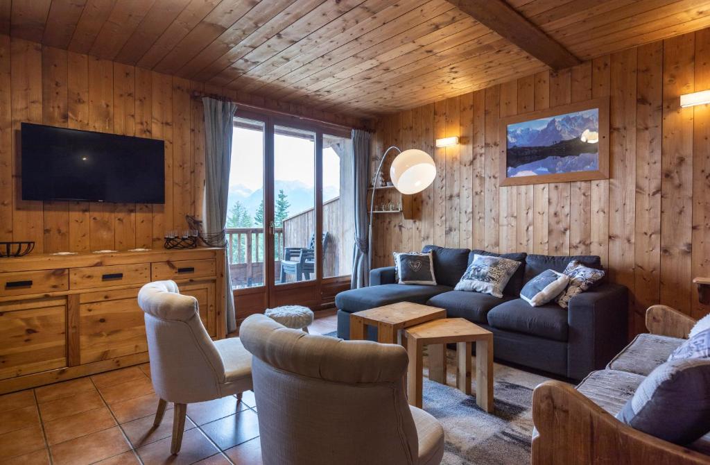 a living room with a couch and a tv at Chalets Kandahar - Mountain Collection in La Rosière