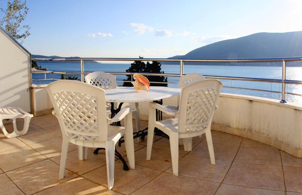 una mesa y sillas en un balcón con vistas al agua en Apartments Villa Kukoljac, en Herceg-Novi