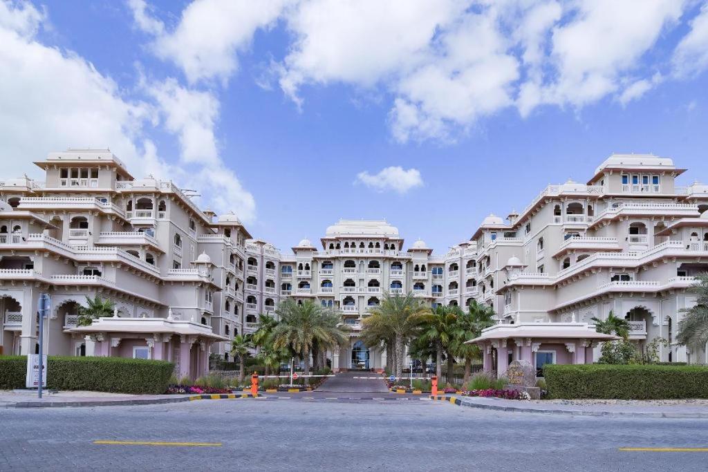 a large white building with palm trees in front of it at Royal Club By RVHR, Grandeur Residence Crescent Palm Jumeirah in Dubai