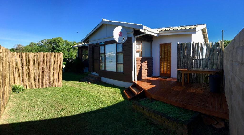 a small house with a wooden deck in the yard at David Bongers Still Bay Holiday Home in Stilbaai