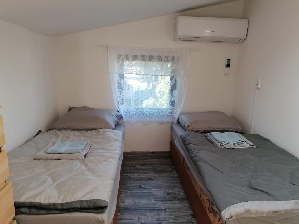 two beds in a small room with a window at Apartmán se zahradou pro dvě osoby v turisticky oblíbené lokalitě in Weisswasser in Böhmen