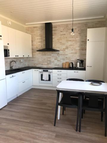 a kitchen with white cabinets and a table in it at Soda Home - Karlsbo, 24 h check in in Närpiö