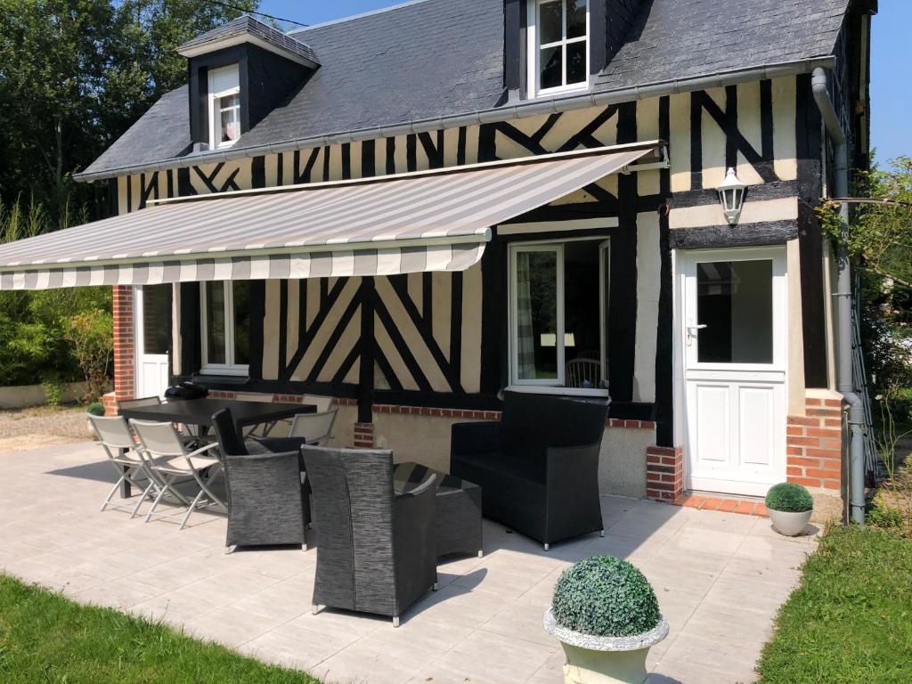 un patio con mesa y sillas frente a una casa en La Maison de Sophie 10mn de Deauville, en Tourgéville