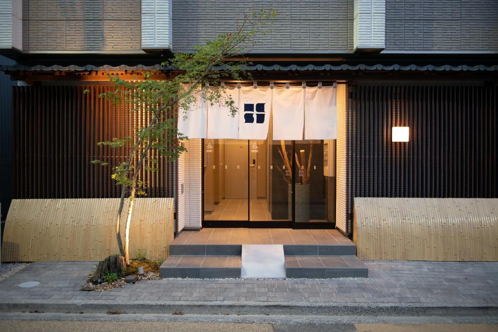 eine Tür zu einem Gebäude mit einem Baum davor in der Unterkunft Hotel Celeste Shizuoka in Shizuoka