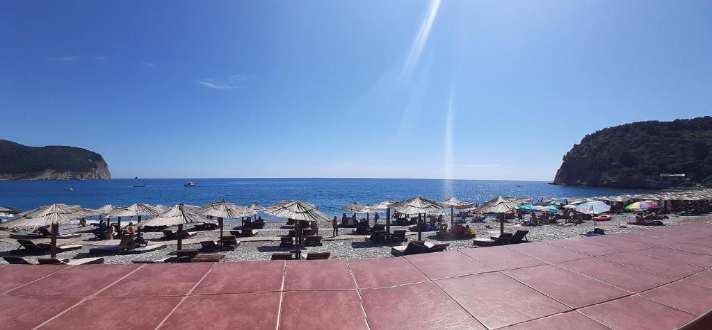 a beach with chairs and umbrellas and the ocean at Beach House Buljarica in Petrovac na Moru