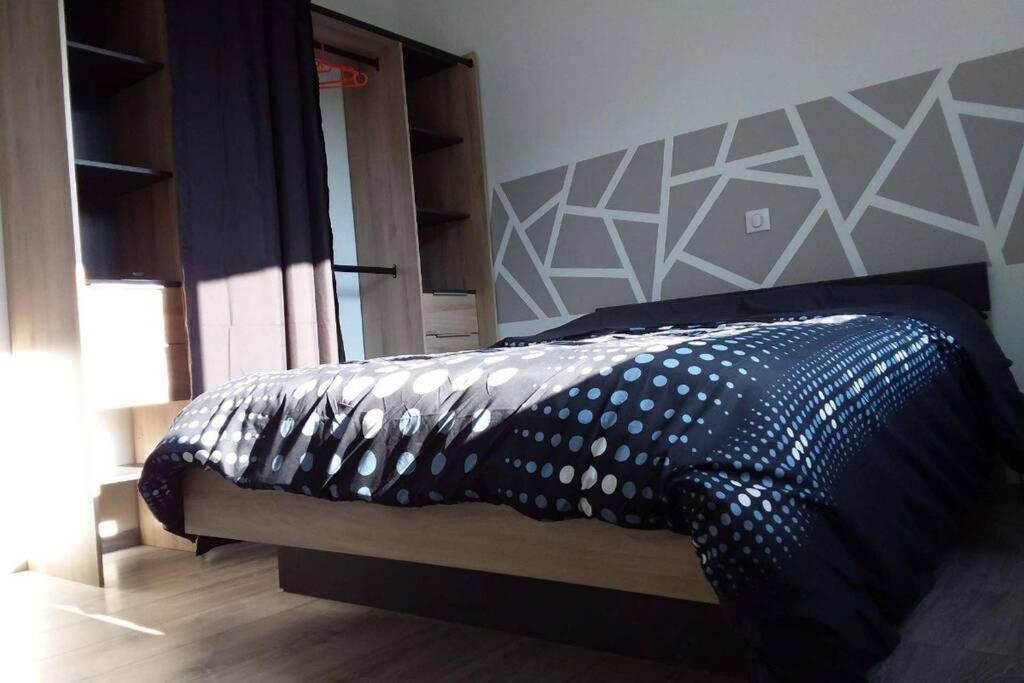 a bed with a black and white comforter in a bedroom at Maison Lulalilo in Crémeaux