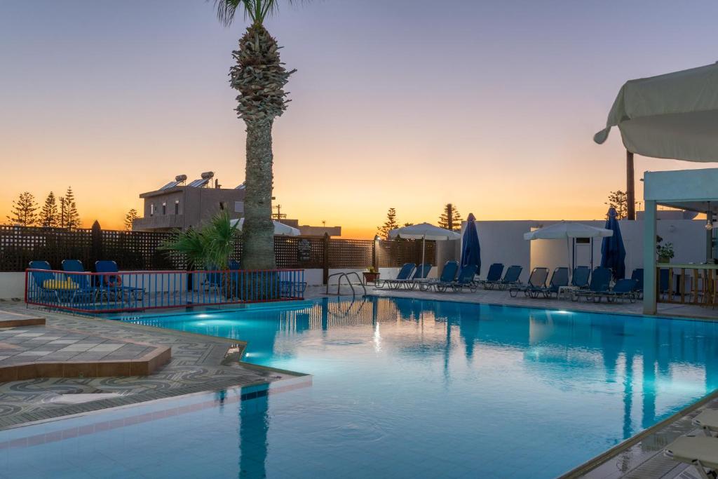 a swimming pool with a palm tree in the background at Marie Κelly Apartments in Gouves