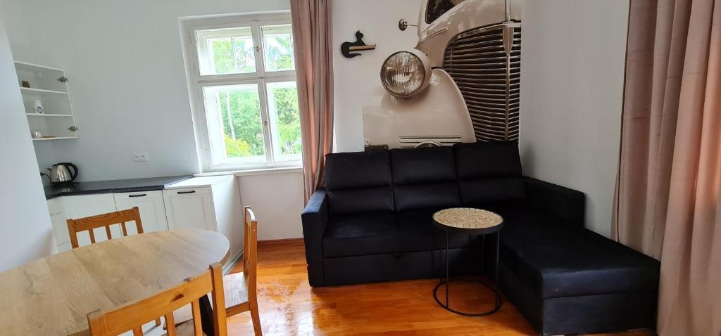 a living room with a black couch and a table at Apartamenty EverySky - Konstytucji 3 go Maja 66-2 in Karpacz