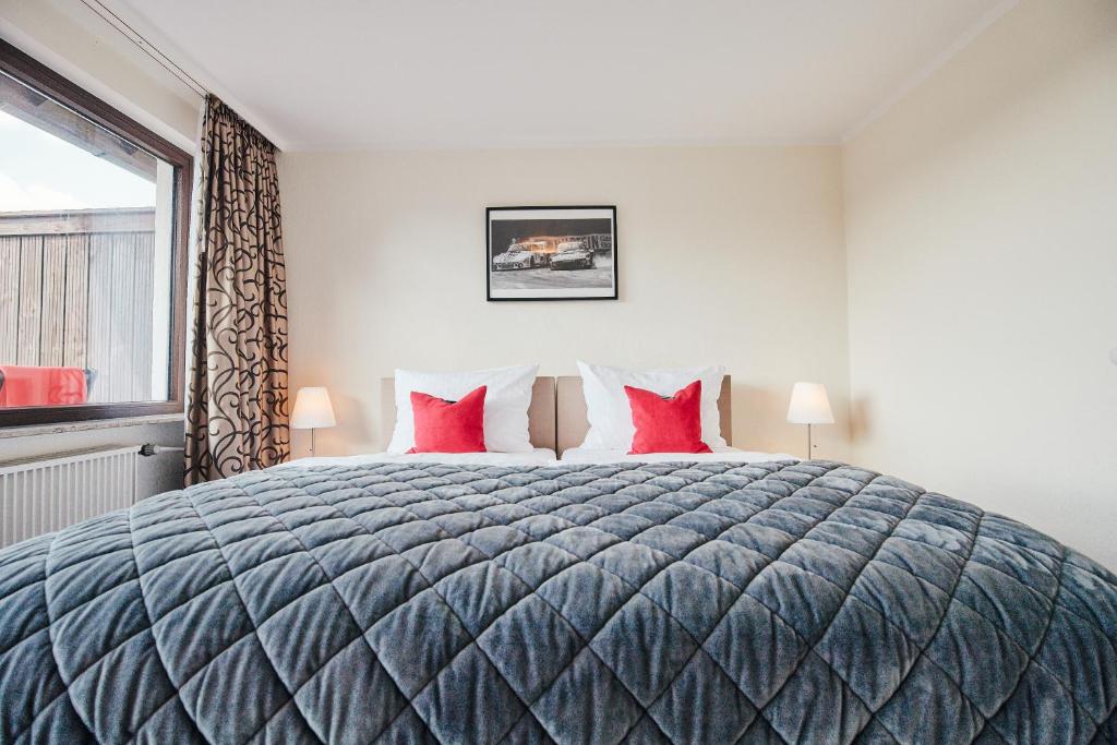 1 dormitorio con 1 cama grande con almohadas rojas en Hotel Parc Fermé en Siebenbach