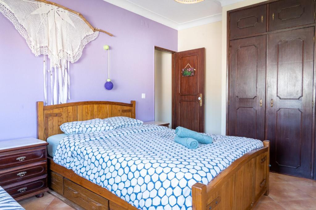 a bedroom with a wooden bed with a blue pillow on it at Natural Mystic Hostel in Costa da Caparica