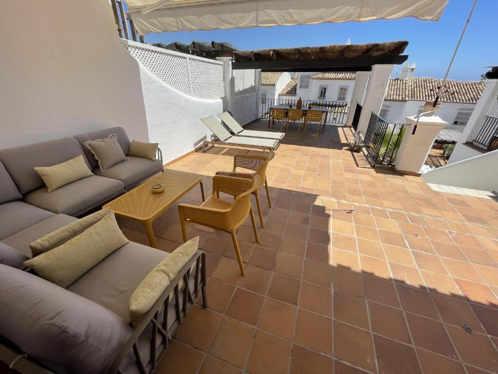 un patio con sofá, mesas y sillas en Casa Carino, en La Herradura
