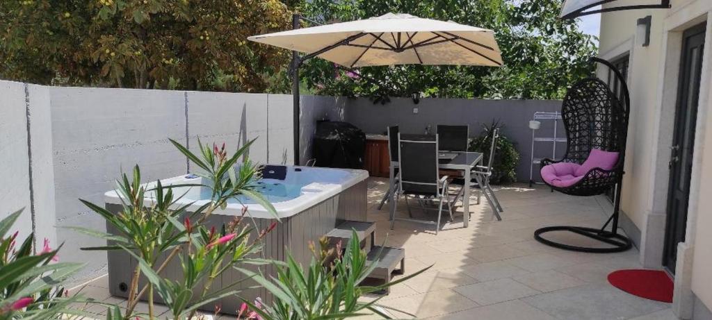 um pátio com uma banheira de hidromassagem e um guarda-sol em Casa Percan em Premantura