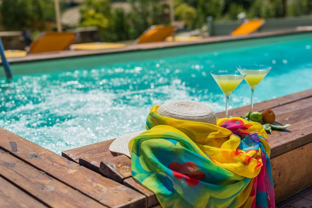 a pool with two drinks and a towel next to a swimming pool at Casa Magica in San Lorenzo in Campo