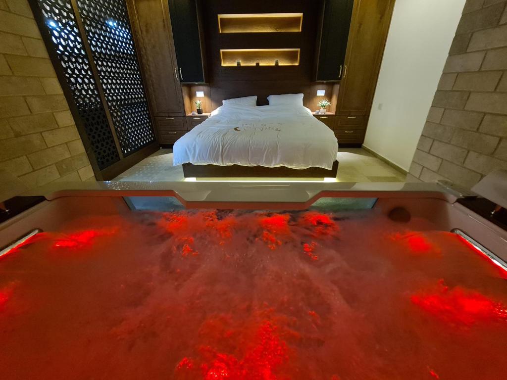 Schlafzimmer mit einem Bett und einer Badewanne mit rotem Wasser in der Unterkunft סוויטת נור Noor Suite in Madschdal Schams