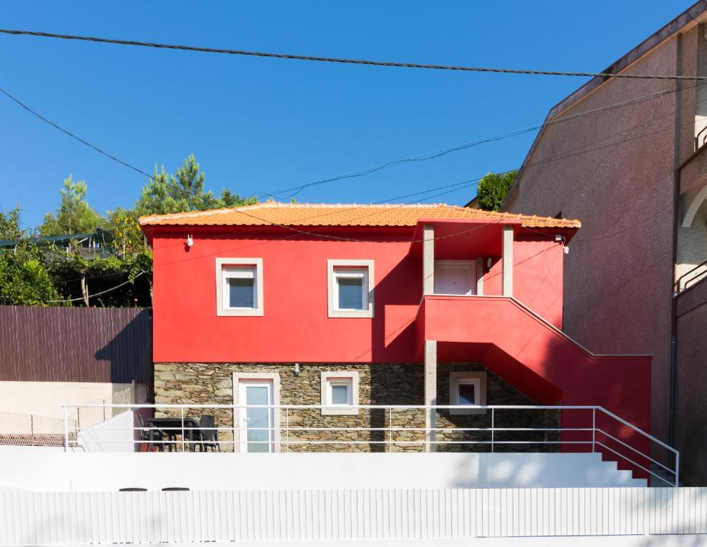 Red House Douro River Marina في جوندومار: منزل احمر على جانب مبنى