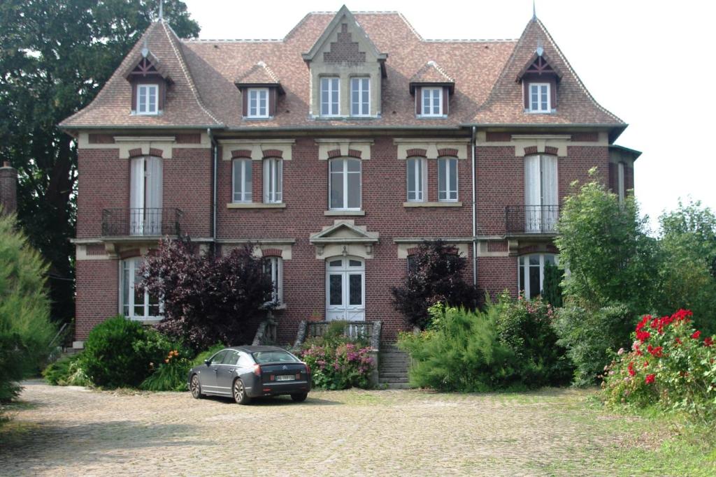 Le Manoir de Crisolles في Crisolles: منزل فيه سيارة متوقفة أمامه