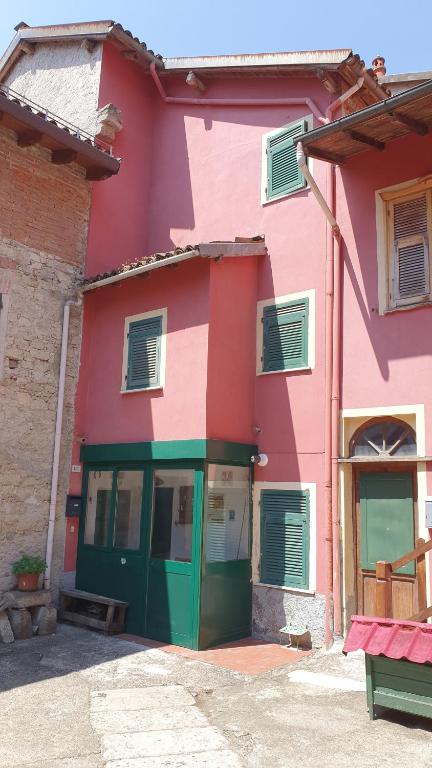 un edificio rosa y verde con una puerta verde en Casa vacanza Pegrini nel centro storico di Gavi, en Gavi