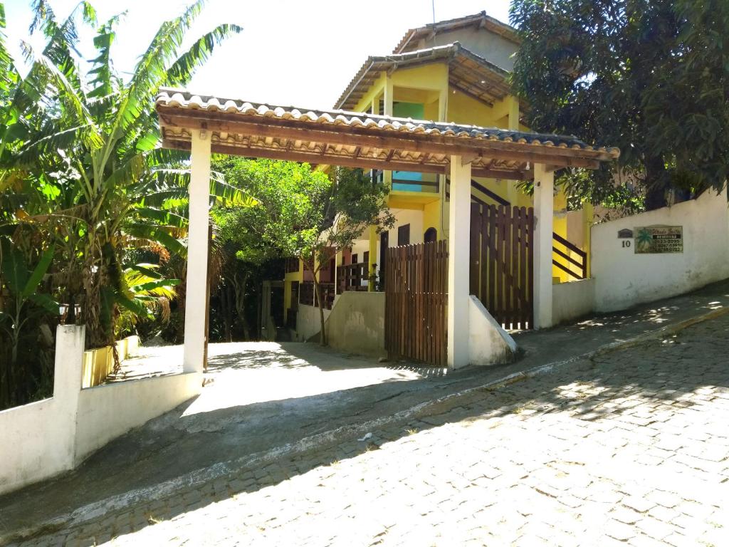 a gate to a yellow house with a fence at Wando Suítes in Búzios