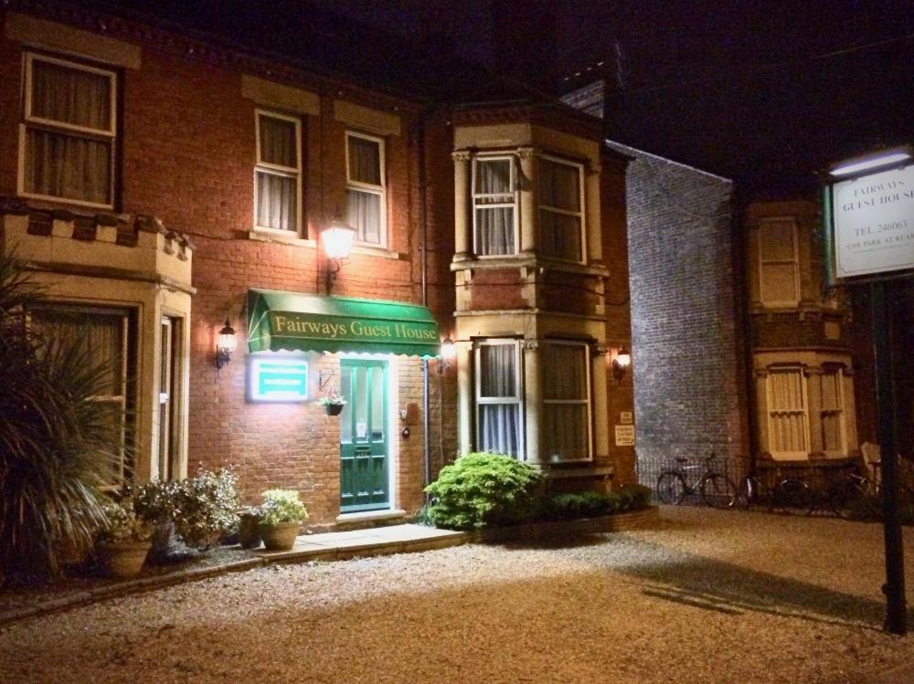 a brick building with a green sign in front of it at Fairways Guest House in Cambridge