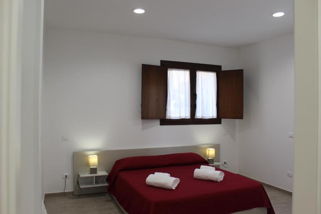 クストナーチにあるcasa sandrina piano terraのベッドルーム1室(赤いベッド1台、タオル2枚付)
