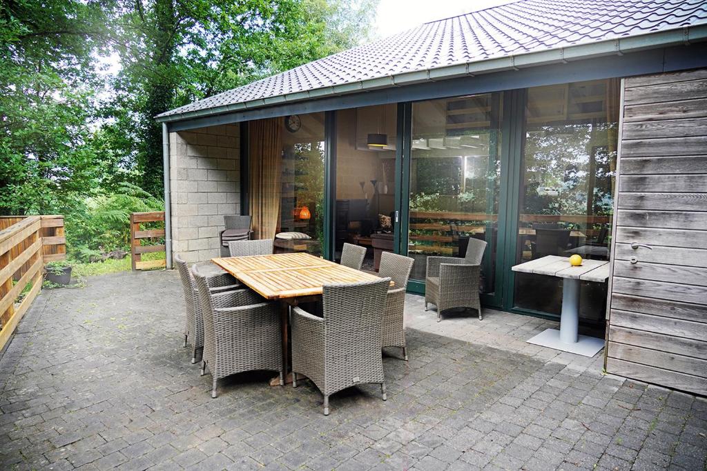 een patio met een houten tafel en stoelen bij Le Vieux Sart 6 Coo Spa Francorchamps in Stavelot