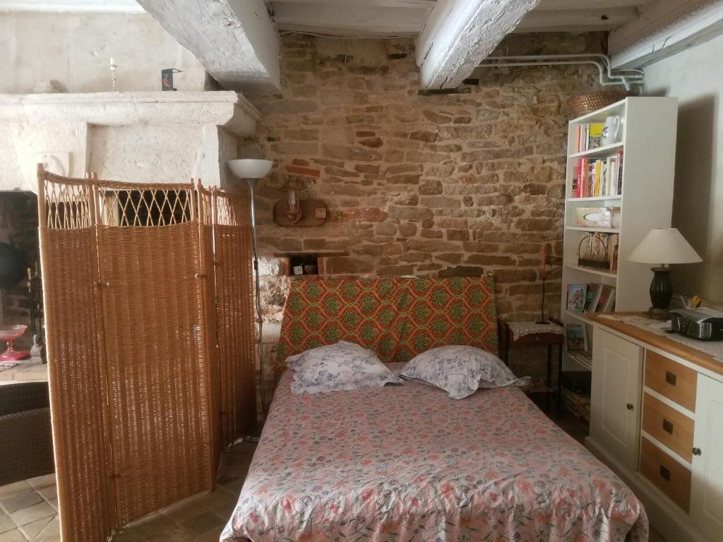 1 dormitorio con cama y pared de ladrillo en Le Colimaçon, en Cluny