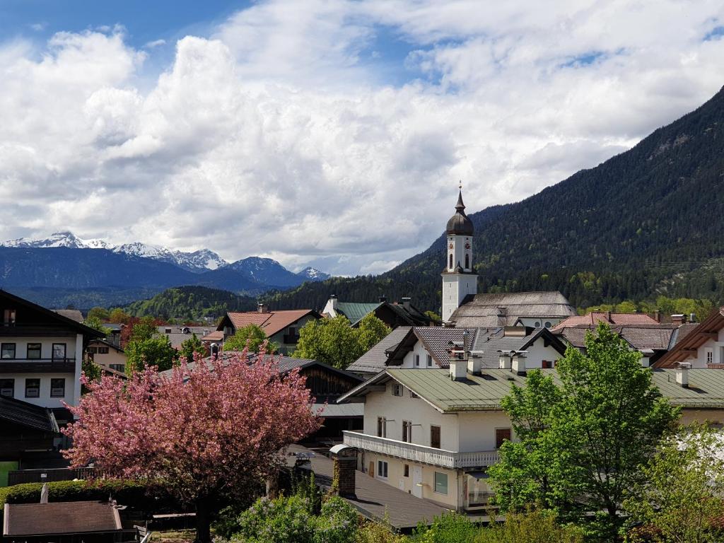 une ville avec une tour d'horloge et des montagnes en arrière-plan dans l'établissement Bunter Hirsch Ferienwohnung im Garmischer Zentrum, à Garmisch-Partenkirchen