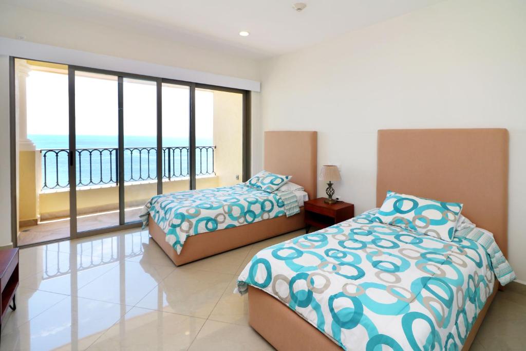 Un dormitorio con dos camas y un balcón con vista al mar. en GAVIAS GRAND MAZATLAN APT. 1415, en Mazatlán
