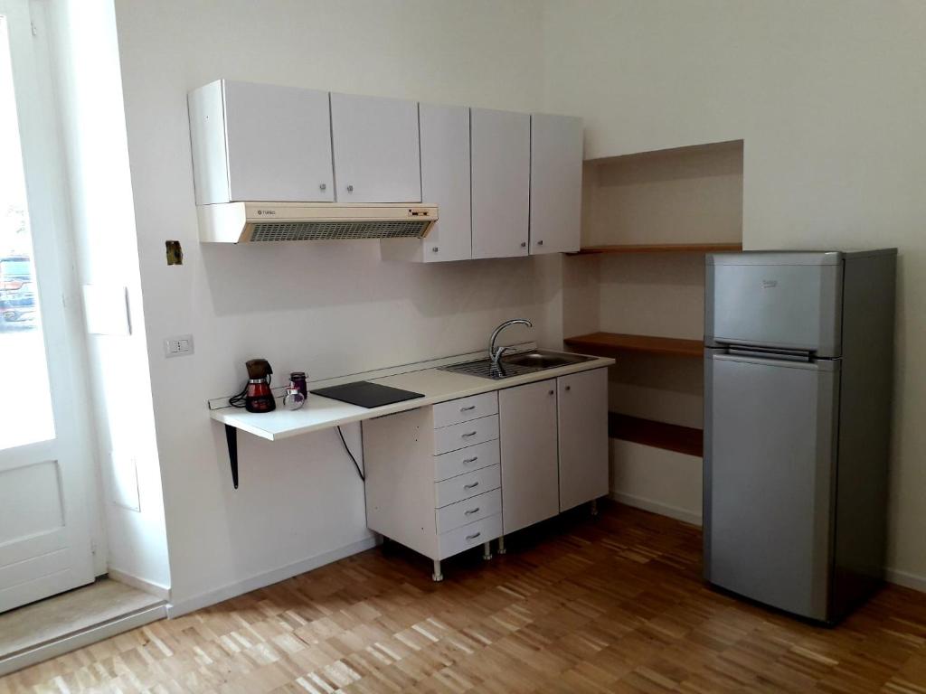 a small kitchen with white cabinets and a refrigerator at La Casa del Dottore in Rapolla
