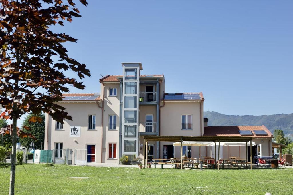 un grande edificio con tavoli e sedie in un campo di Ostello La Salana a Capannori