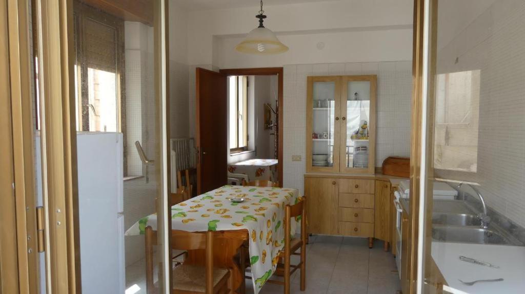 a kitchen with a table and a sink and a refrigerator at Appartamento fronte mare San vito lo capo in San Vito lo Capo