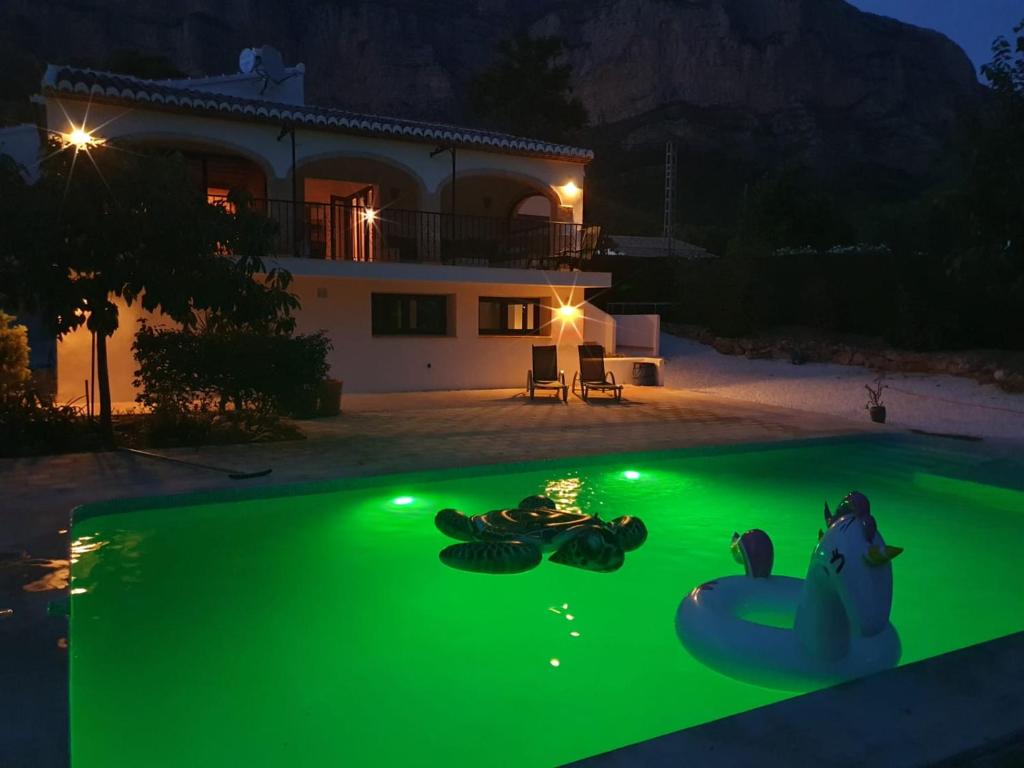 una piscina con luz verde frente a una casa en Apartemento América en Jávea