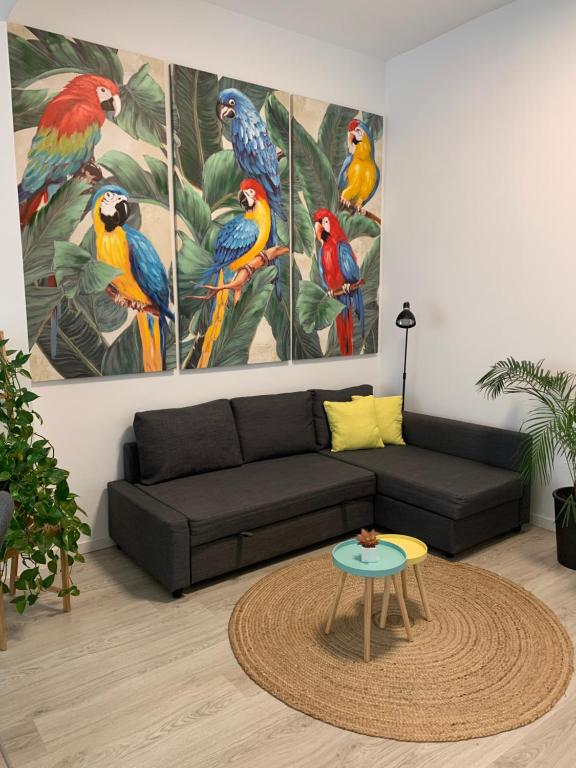 a living room with a black couch and four parrots at CASA PAPAGAYO in Santa Cruz de Tenerife