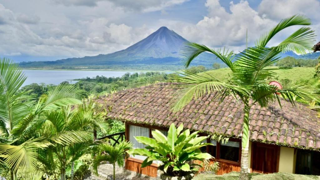 a house with a mountain in the background with palm trees at Pie in the Sky 1 Gorgeous Cottage with spectacular scenic views in El Fosforo