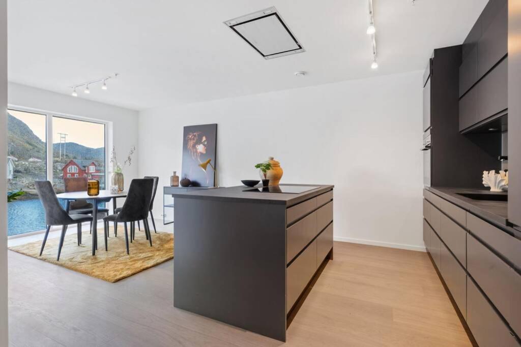 a kitchen with a counter and a dining room with a table at Gjermundsøya Brygge in Ballstad