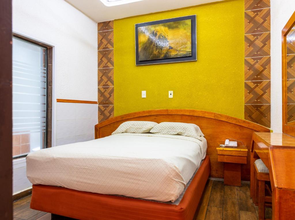 1 dormitorio con cama y pared amarilla en Hotel Vista Alegre en Ciudad de México