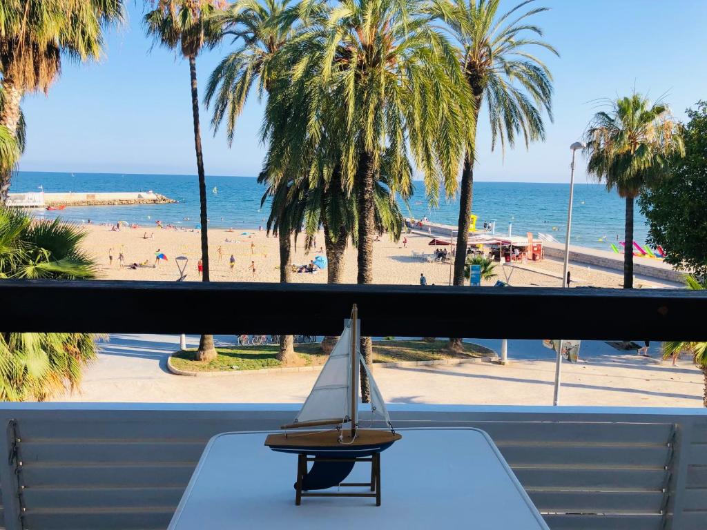 a small sail boat on a table in front of a beach at Fragata Beach Seaview in Sitges