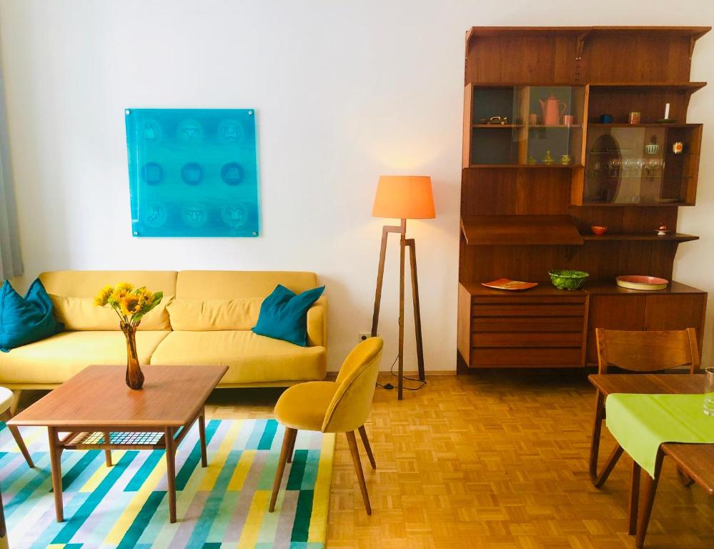 ein Wohnzimmer mit einem gelben Sofa und einem Tisch in der Unterkunft Vintage Design Apartments in Wien