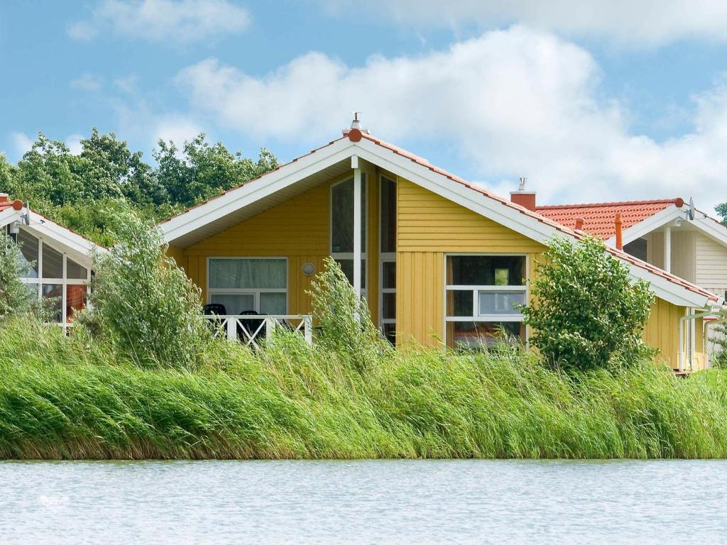a yellow house on the banks of the water at 12 person holiday home in Otterndorf in Otterndorf