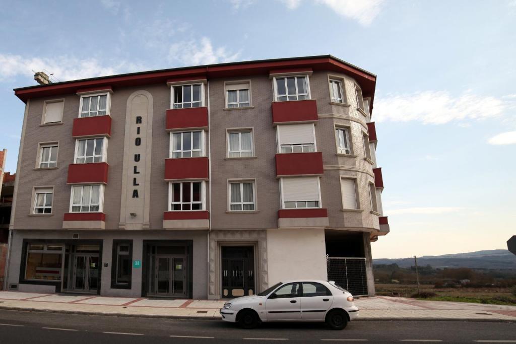 una macchina bianca parcheggiata di fronte a un edificio di Hotel Río Ulla Monterroso a Monterroso
